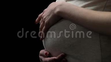 孕妇抚摸被隔离在黑色的腹部，怀孕期间的健康风险